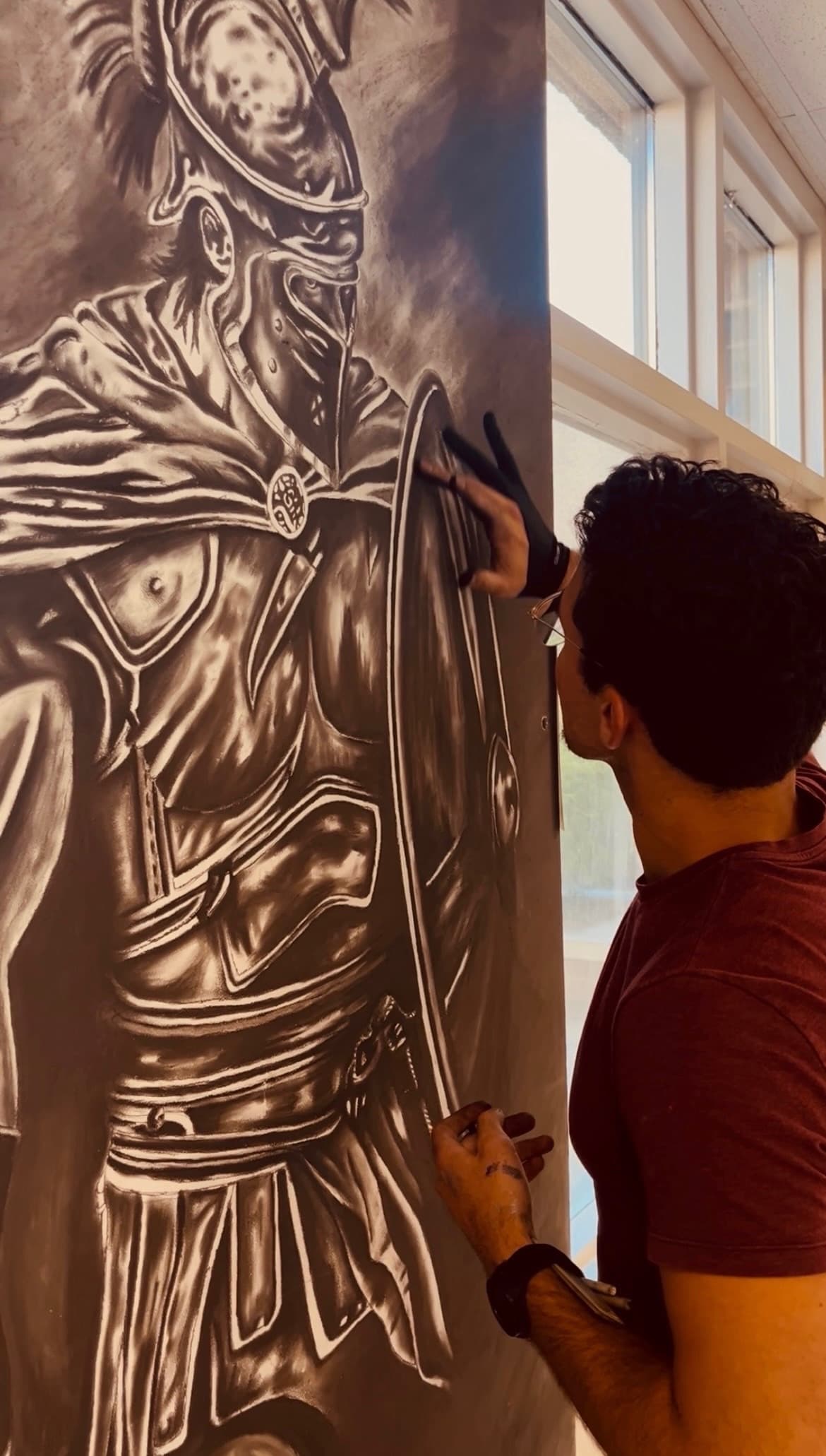 Logan Kiser shading a large charcoal drawing of an armored soldier